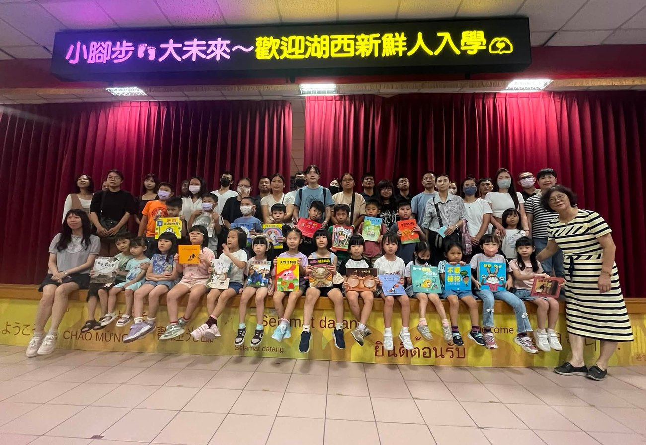湖西國小新生歡迎會，新生與家長於舞台上手持繪本合影