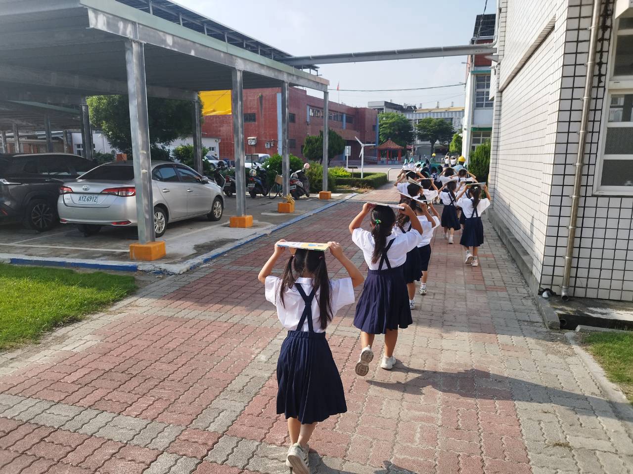 Students walk out with books over their heads 學生用課本護頭疏散