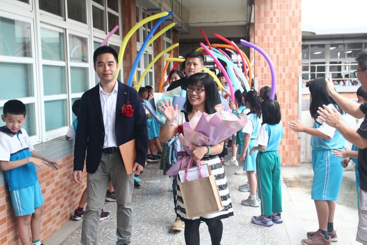 Graduates walking under a balloon archway with teachers and classmates cheering