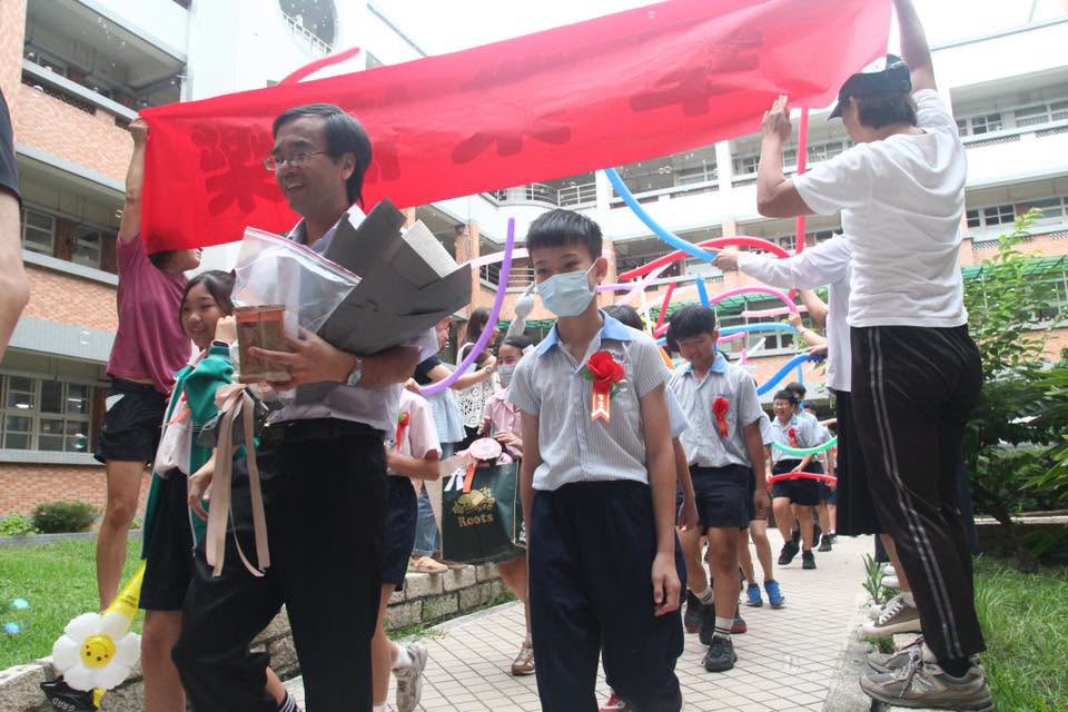 Students and teacher holding a red banner during the graduation walk