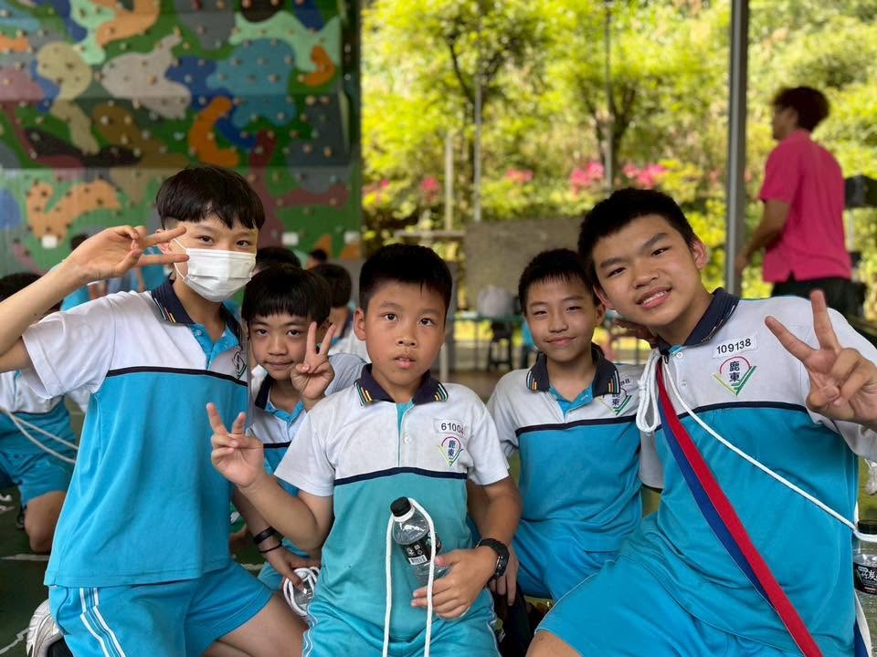 A group of Ludong students smiling in front of the climbing wall