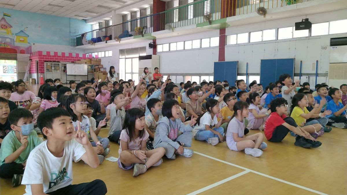 全校學生坐在體育館內專注聆聽，許多人舉手回應