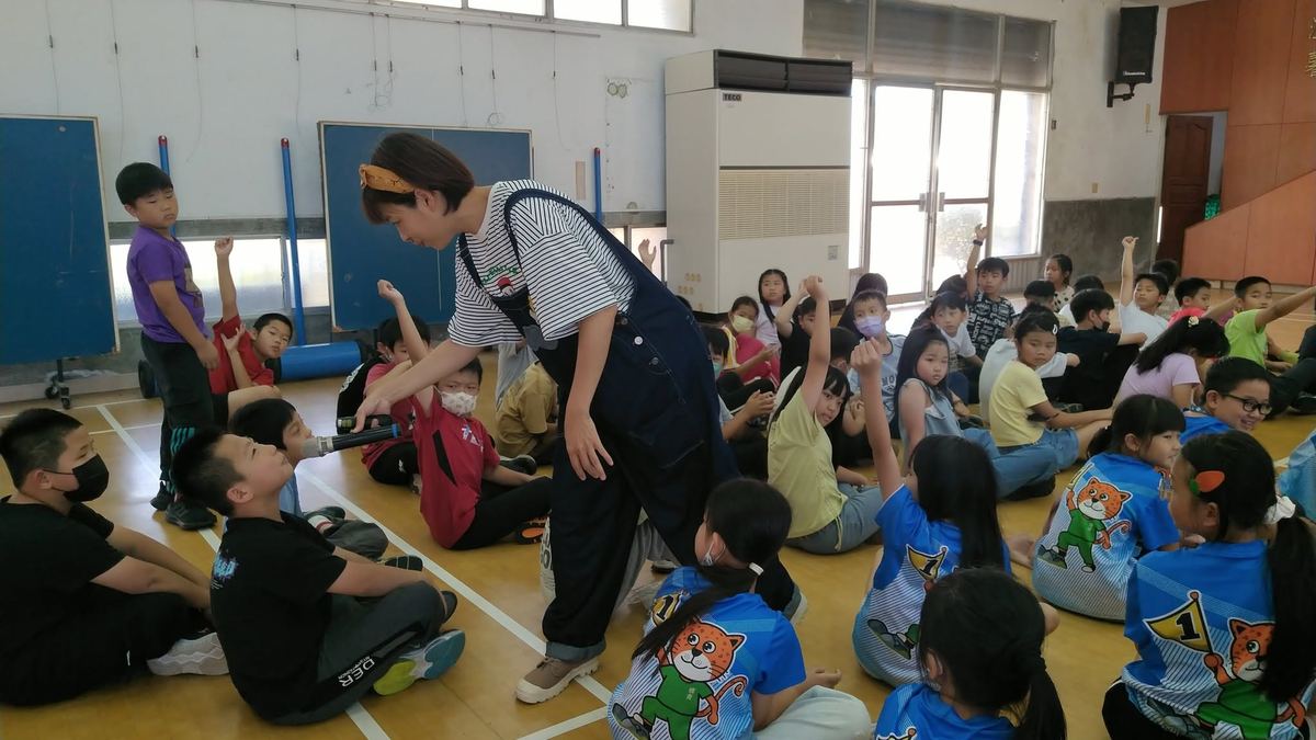 講師手持麥克風彎腰與一位學生互動