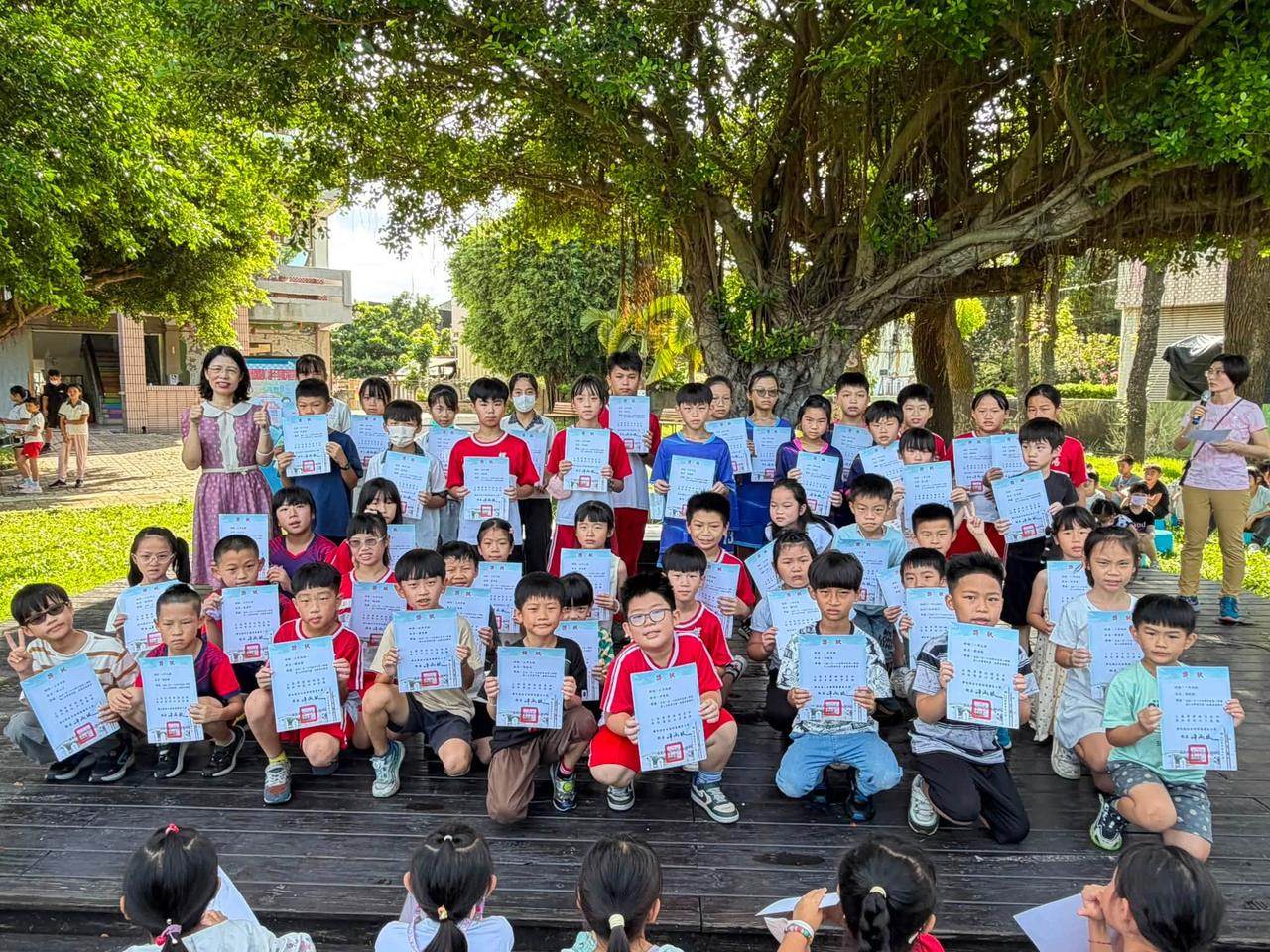 螺陽國小低年級學生在大榕樹下手持獎狀合影