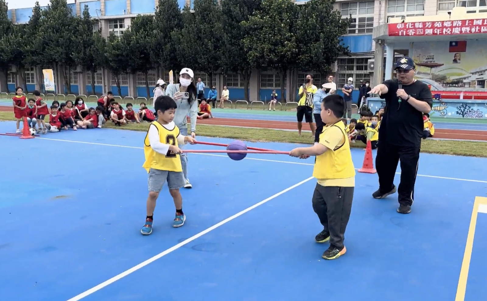 Students playing a stick-and-ball passing game at Lushang's Fun Games