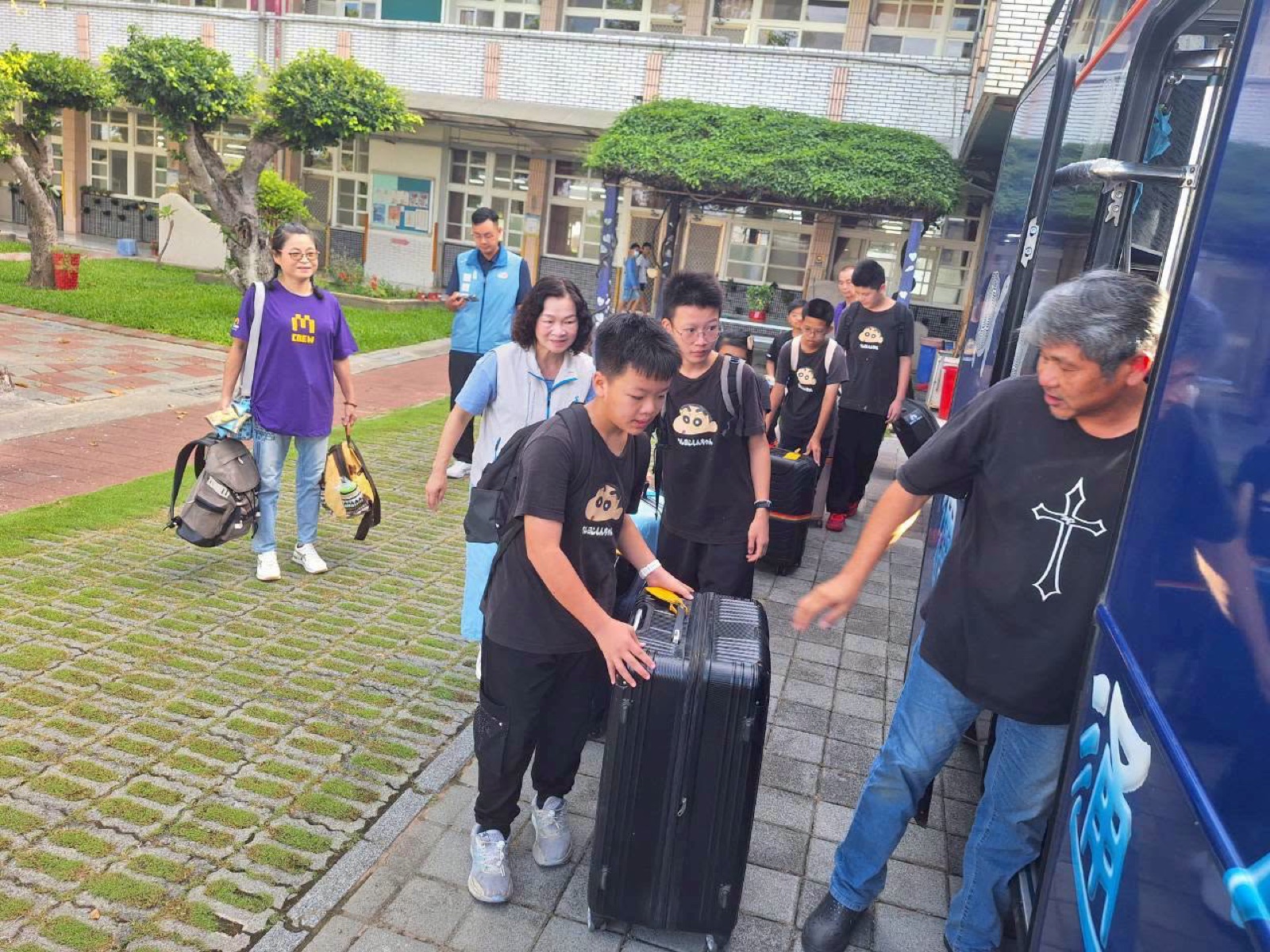 Students wheel their suitcases onto the bus
