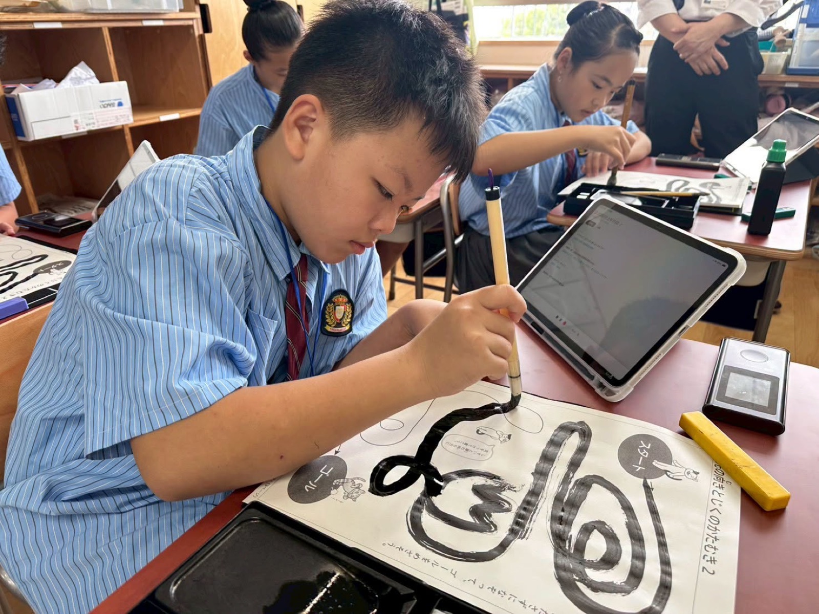 A student carefully paints brush strokes during calligraphy class