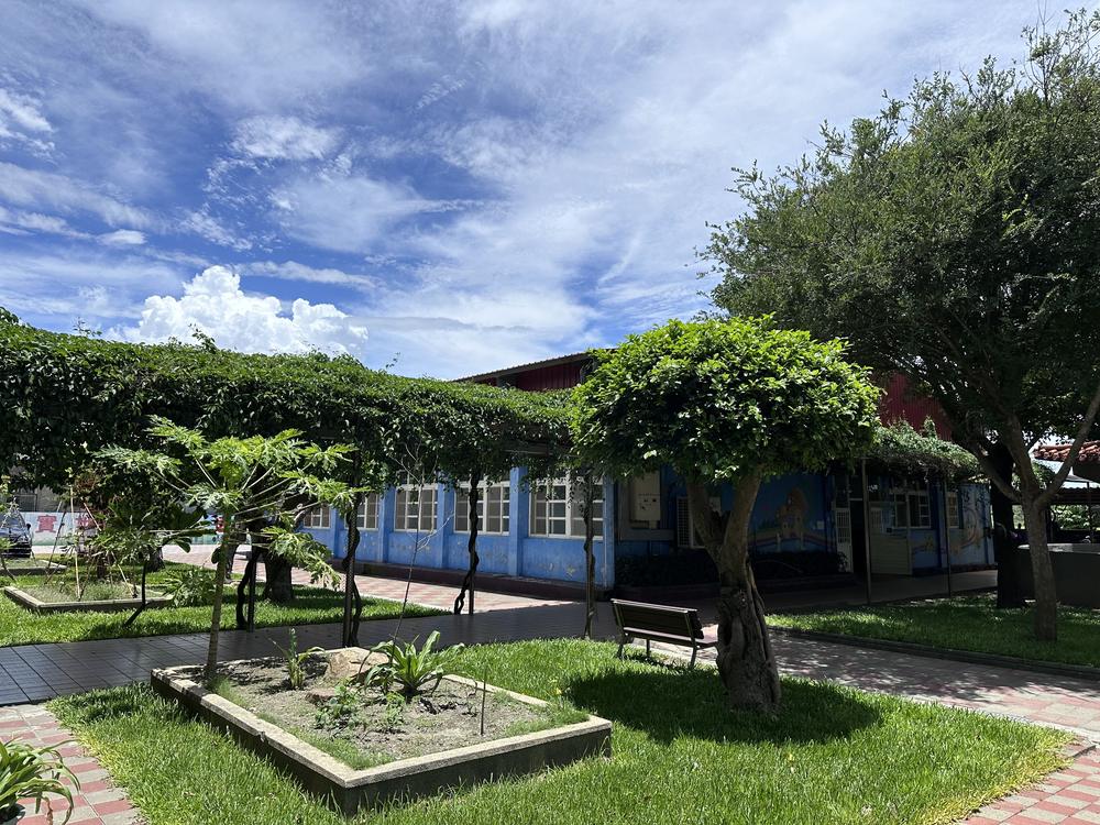 Garden courtyard with a green arbor in front of the blue classrooms