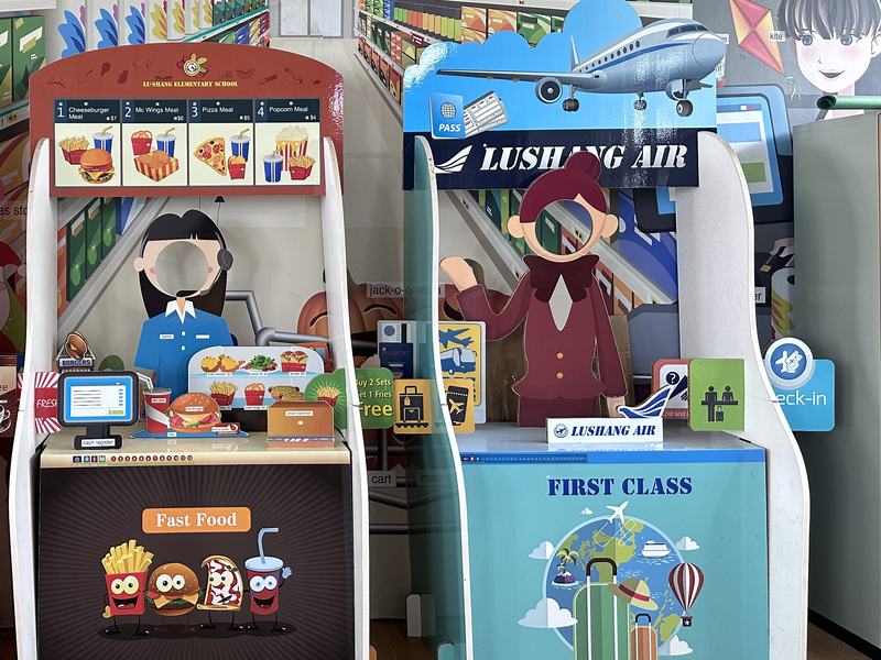 Bilingual role-play corner with a fast-food counter and a Lushang Air check-in desk
