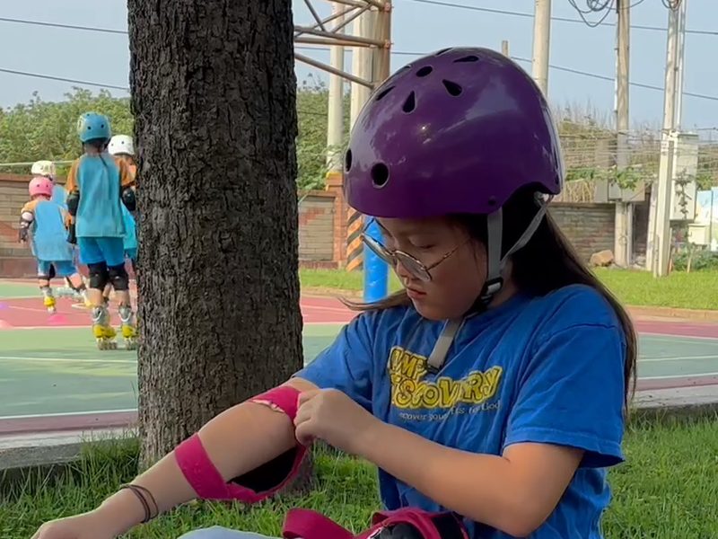 A student pulling an elbow pad over her elbow · 護肘