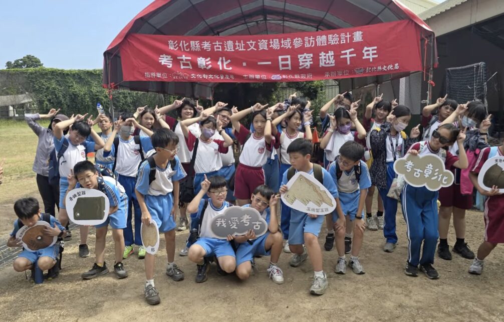 明正國小五年己班學生手持我愛考古立牌與玉玦型玉器模型合影