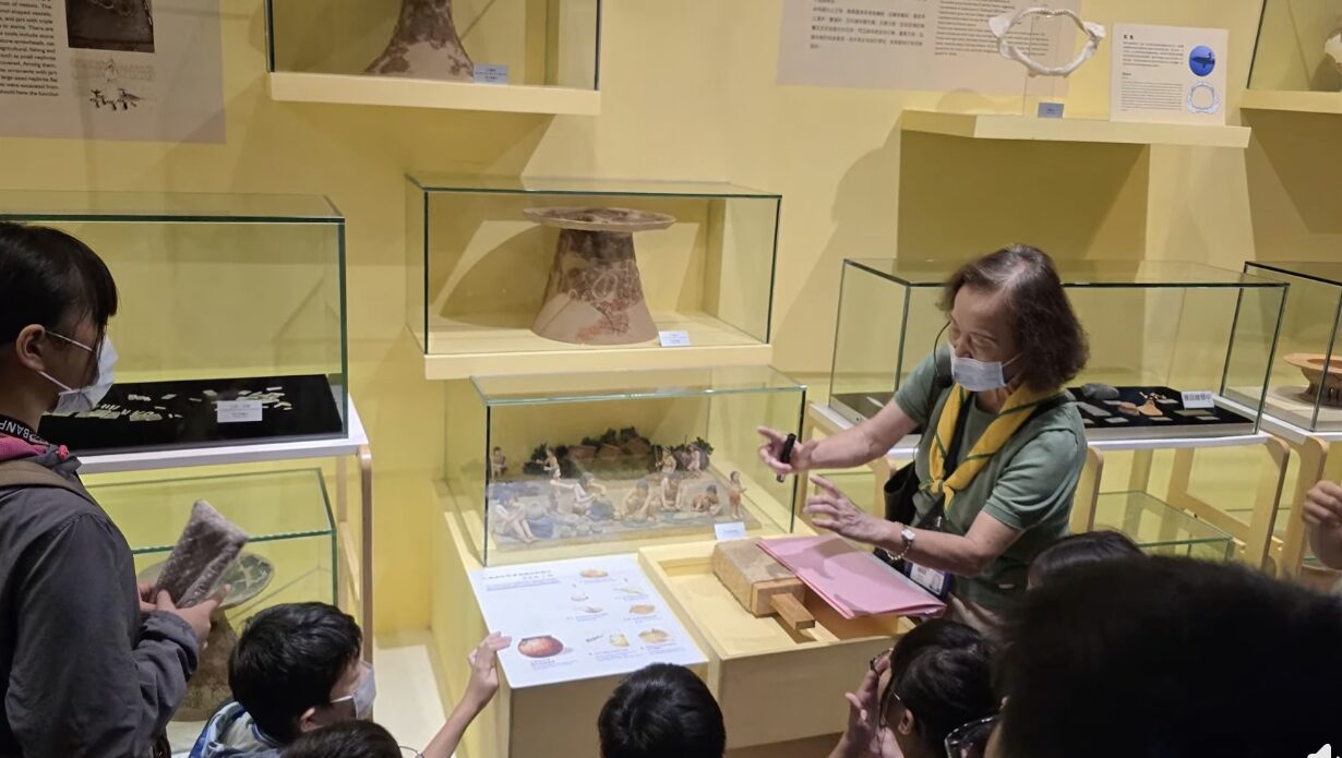 明正國小學生於博物館展櫃前聆聽人員解說陶器與文物模型