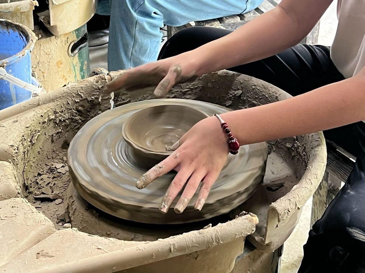 Student shaping clay on a pottery wheel