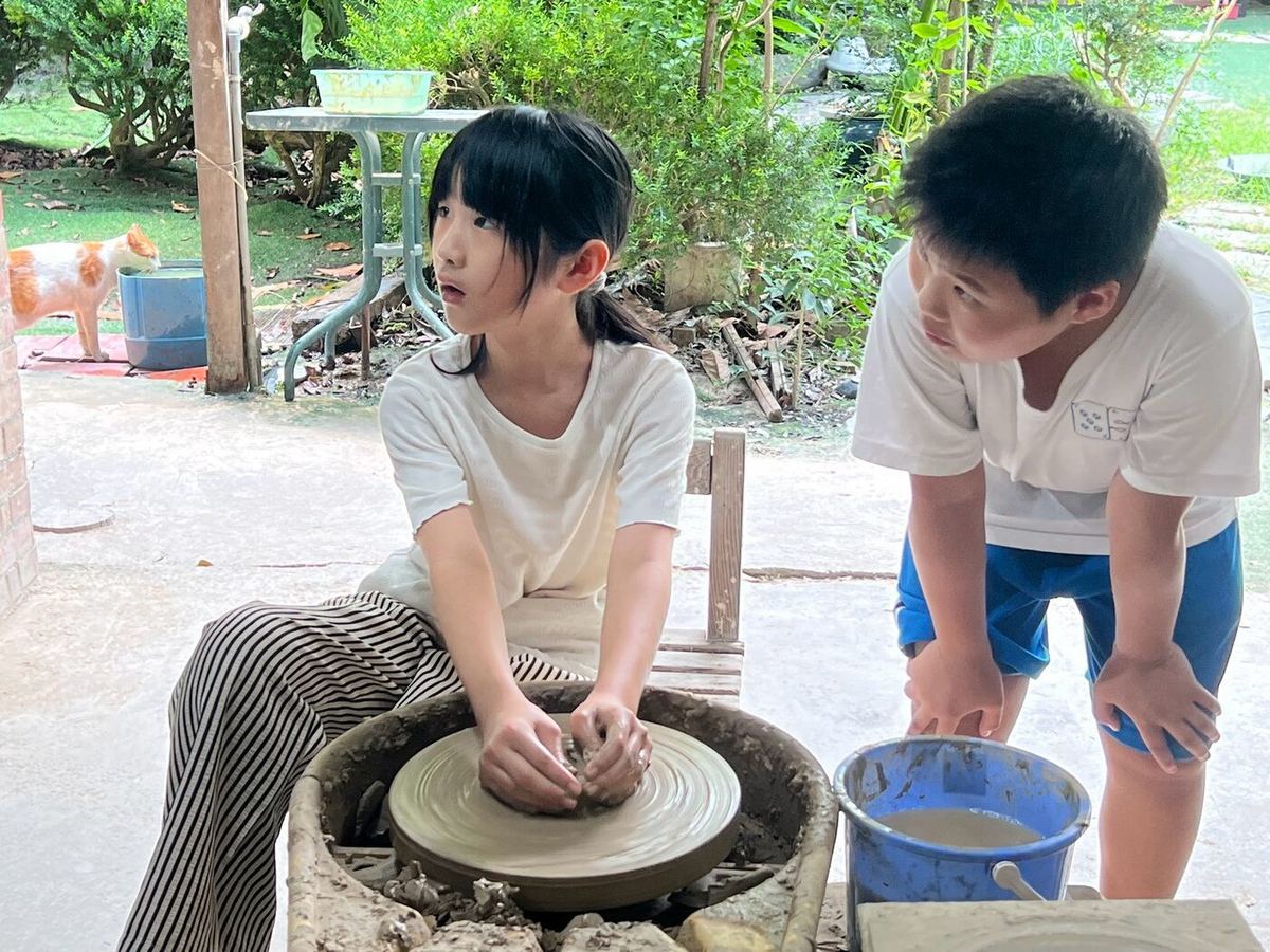Students shaping clay on pottery wheels outdoors