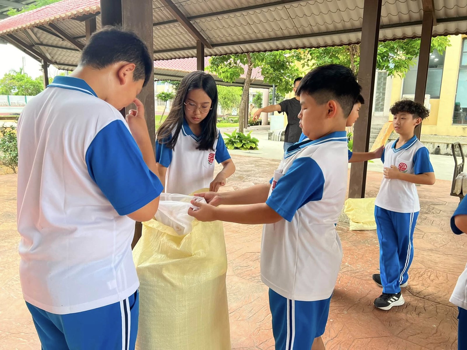 老師指導學生填入粗糠與香草 A teacher helping students fill the pillows with rice husks and herbs