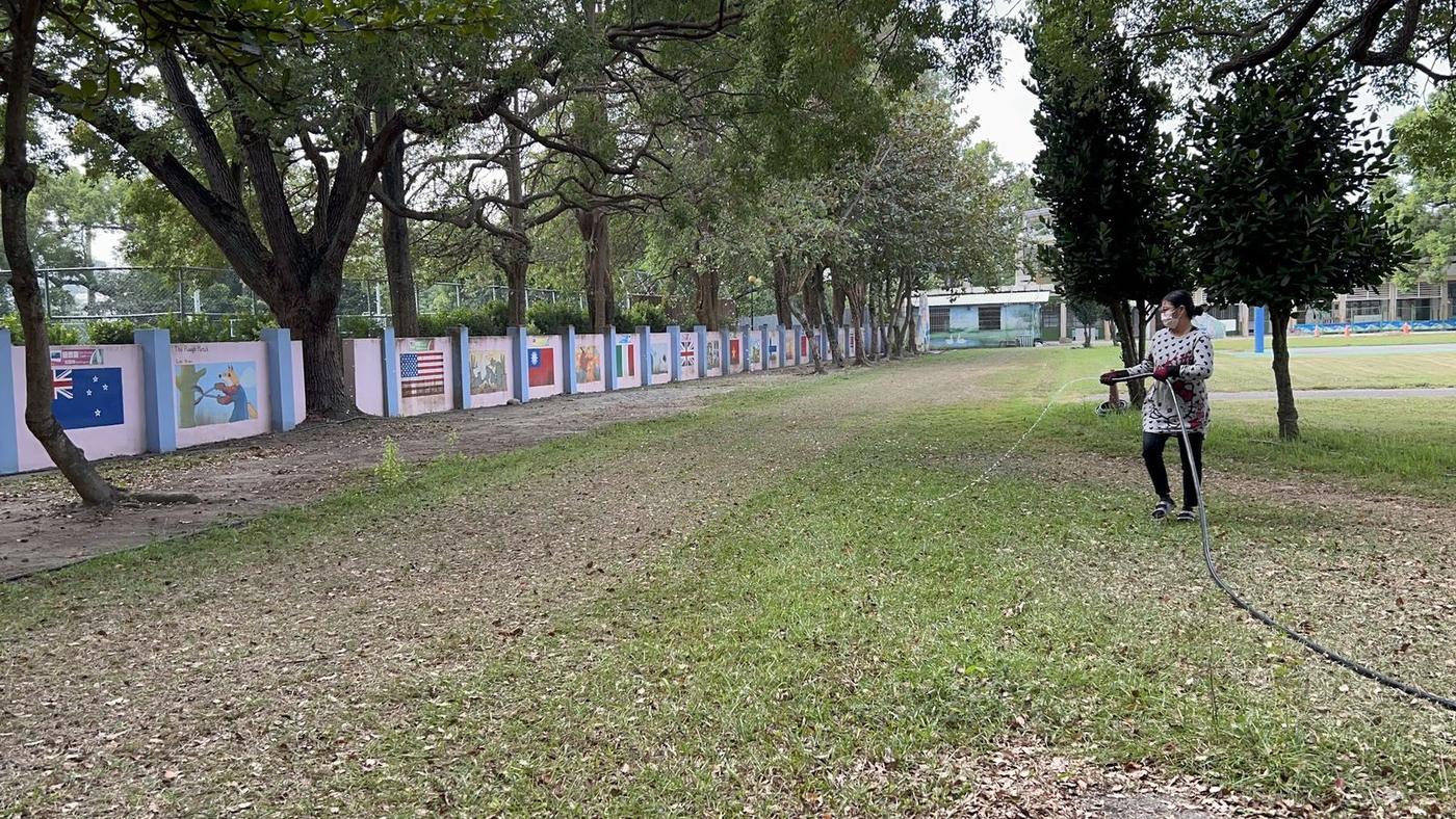 同仁拉著長水管在跑道上人工澆水