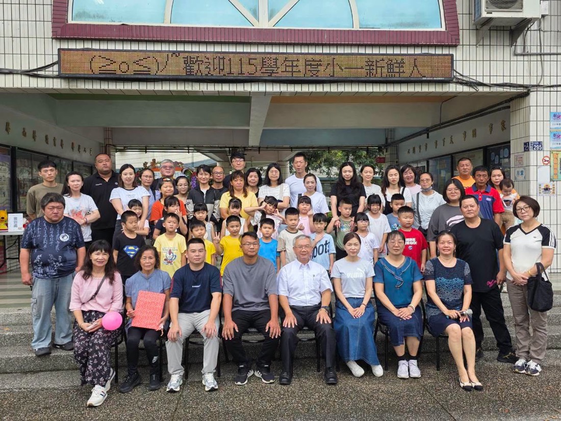 南鎮國小師長與小一新生及家長在「歡迎115學年度小一新鮮人」布條下合影 · Teachers, new first graders and their families under the welcome banner