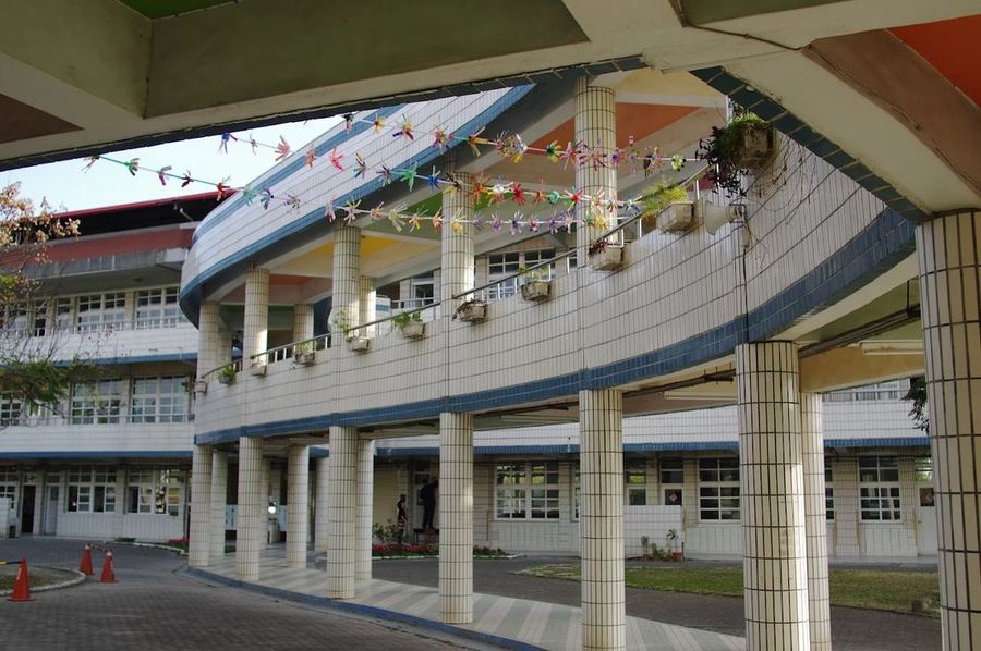 南鎮國小弧形迴廊，欄杆上掛著紙鶴與花盆 The curved walkway at Nanzhen, its railings hung with paper cranes and flower pots