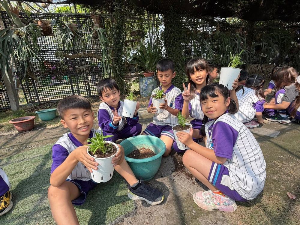 南鎮國小學生蹲在花架下，開心捧著自己親手種的小盆栽 Nanzhen students under a garden trellis, proudly holding the little potted plants they planted themselves