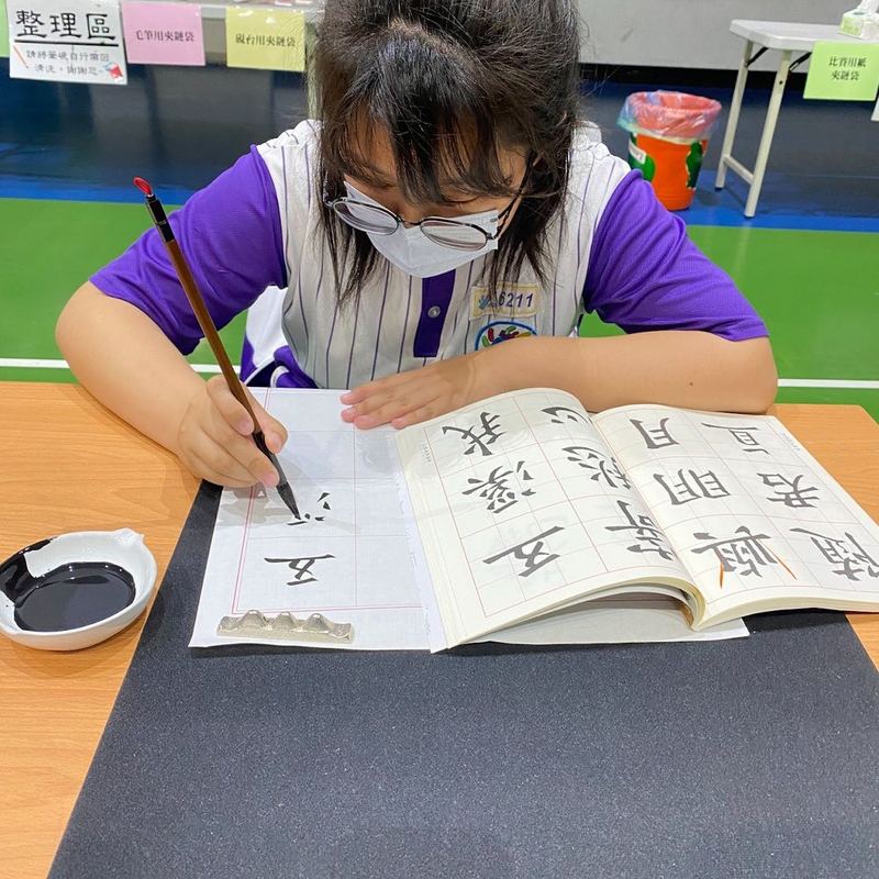 南鎮國小學生專心練習書法，一筆一畫臨帖 A Nanzhen student practicing Chinese calligraphy, copying characters stroke by stroke