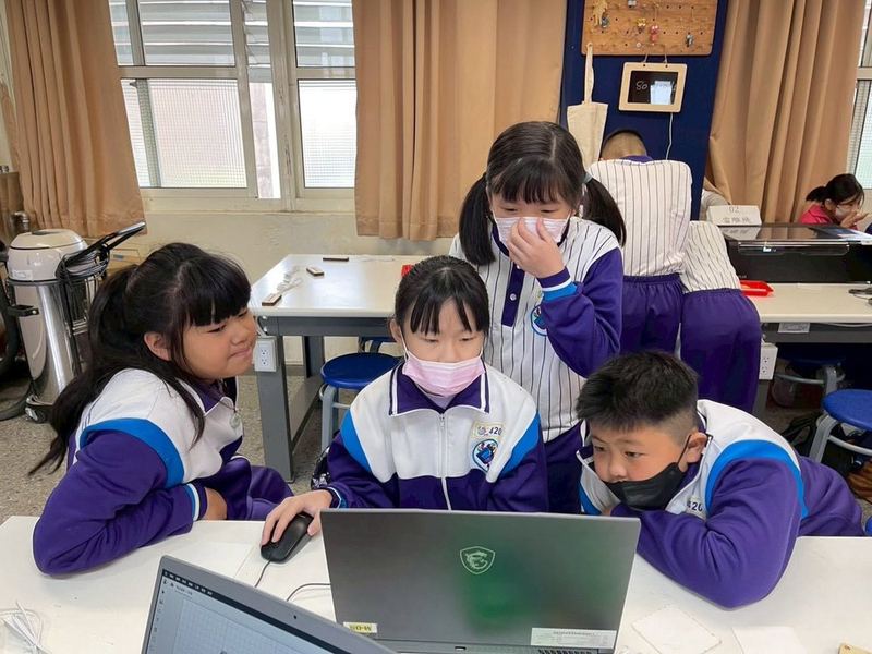 南鎮國小學生圍在筆記型電腦前一起操作 Nanzhen students gathered around a laptop, working on it together