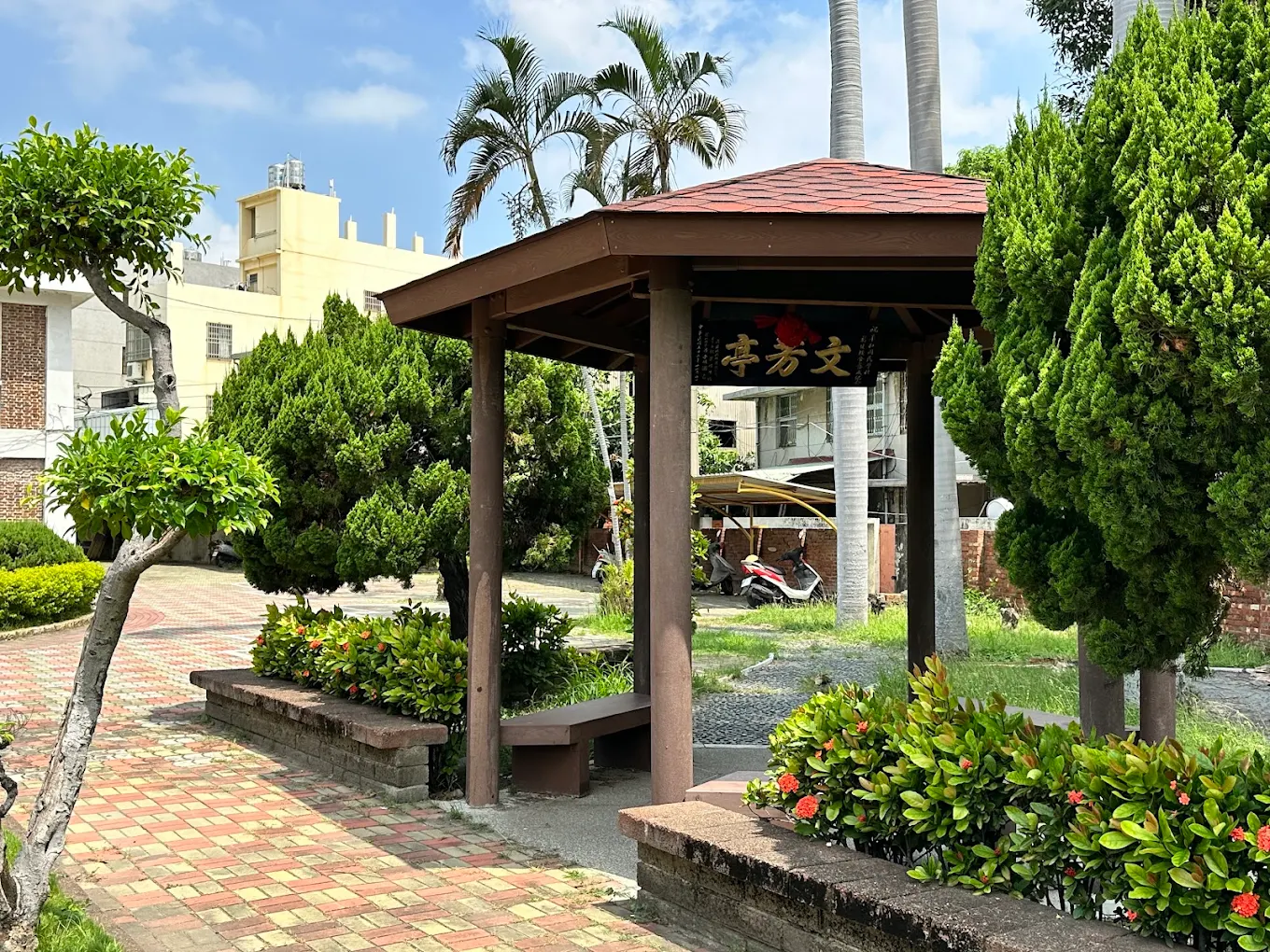 A garden pavilion at Pinghe surrounded by trees and benches 平和國小文芳亭花園