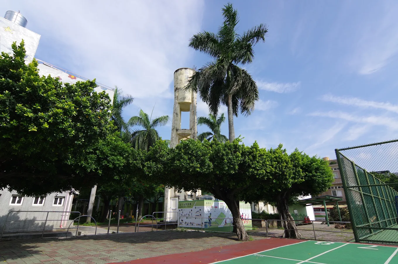 Pinghe's water tower framed by palm trees above the basketball court 平和國小水塔與籃球場