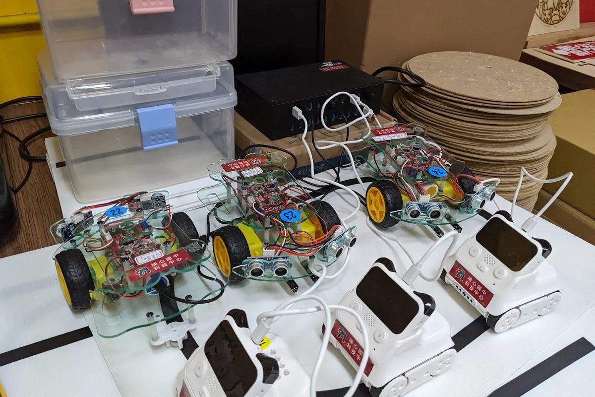 標著「埔心國中科技中心」的自走機器車，連著白色小型機器人 Robot cars labelled 'Pusin JH Technology Centre', wired up to small white robots