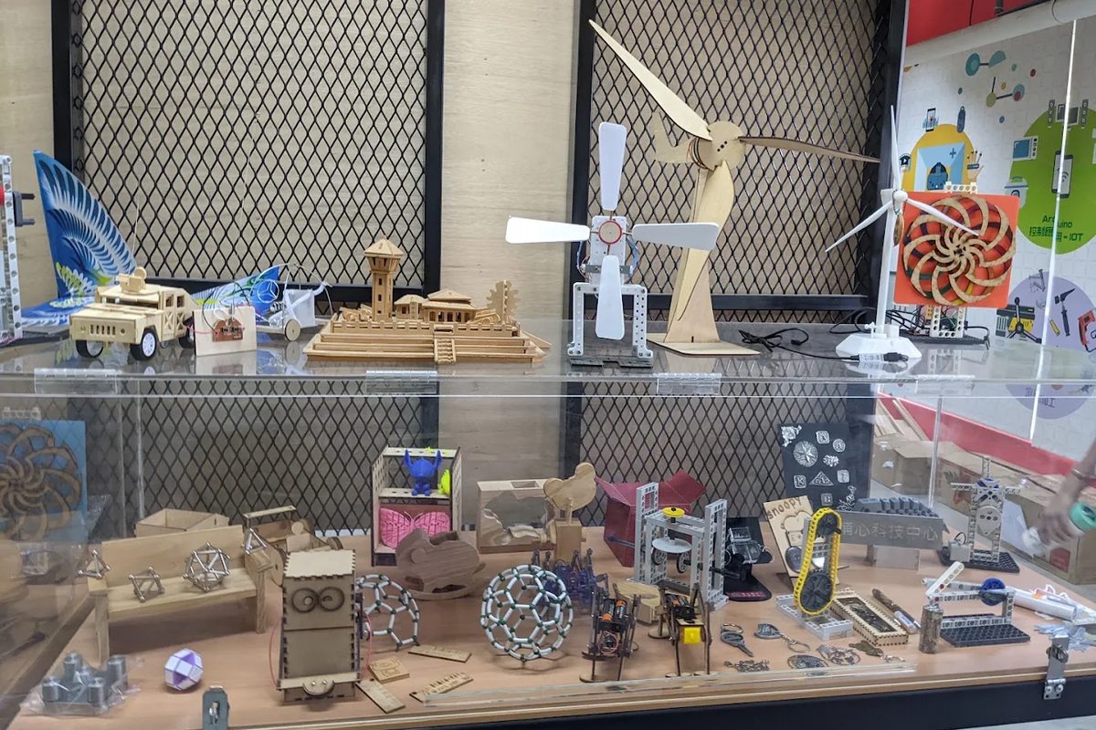 埔心國中科技中心展示櫃裡的木作模型：風車、桁架橋、球形分子結構等學生作品 A display case in the Pusin technology centre with student-built wooden models — windmills, a truss bridge, a spherical molecule model