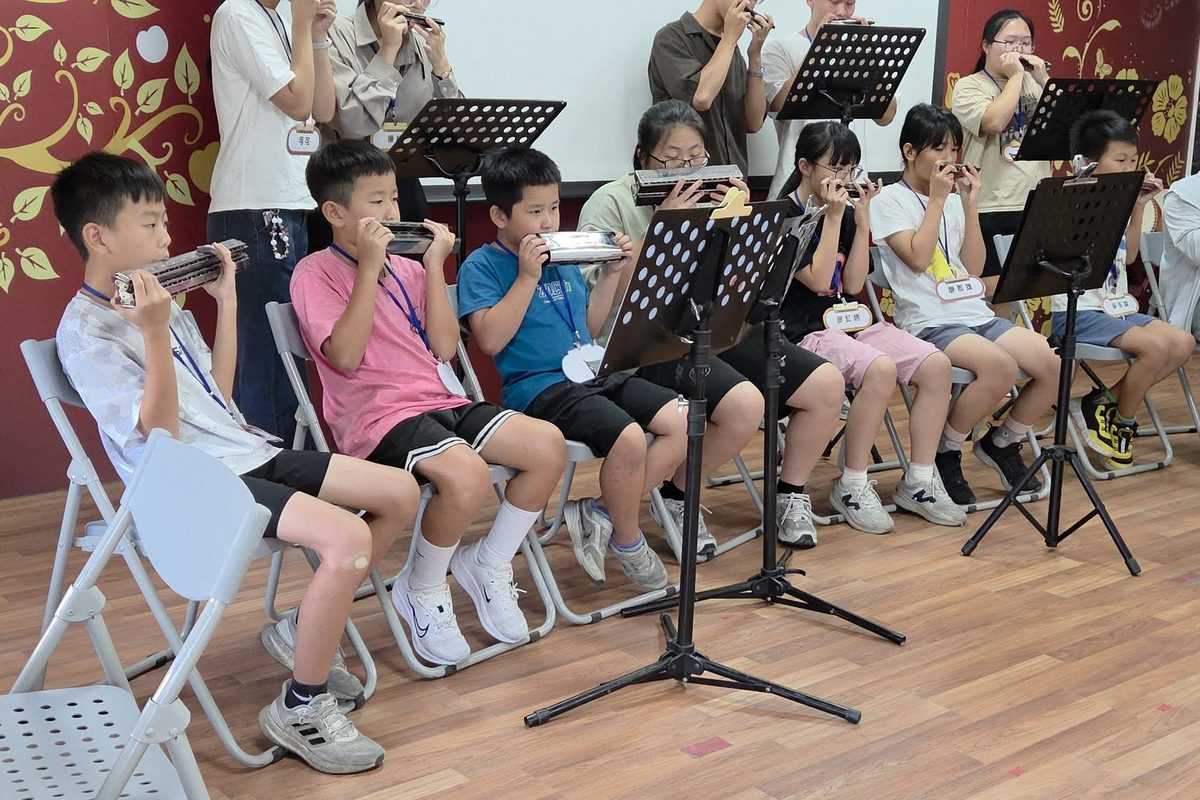 孩子們坐在譜架前練習吹奏口琴