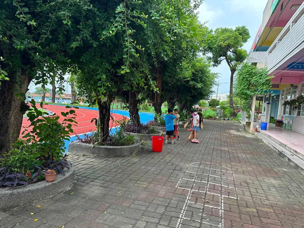 水尾國小學生在校舍旁綠樹成蔭的步道上打掃