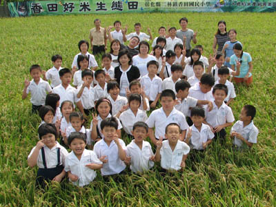 Whole-school class portrait taken in the Siangtian rice paddy, banner reads 香田好米生態田 二林鎮香田國民小學