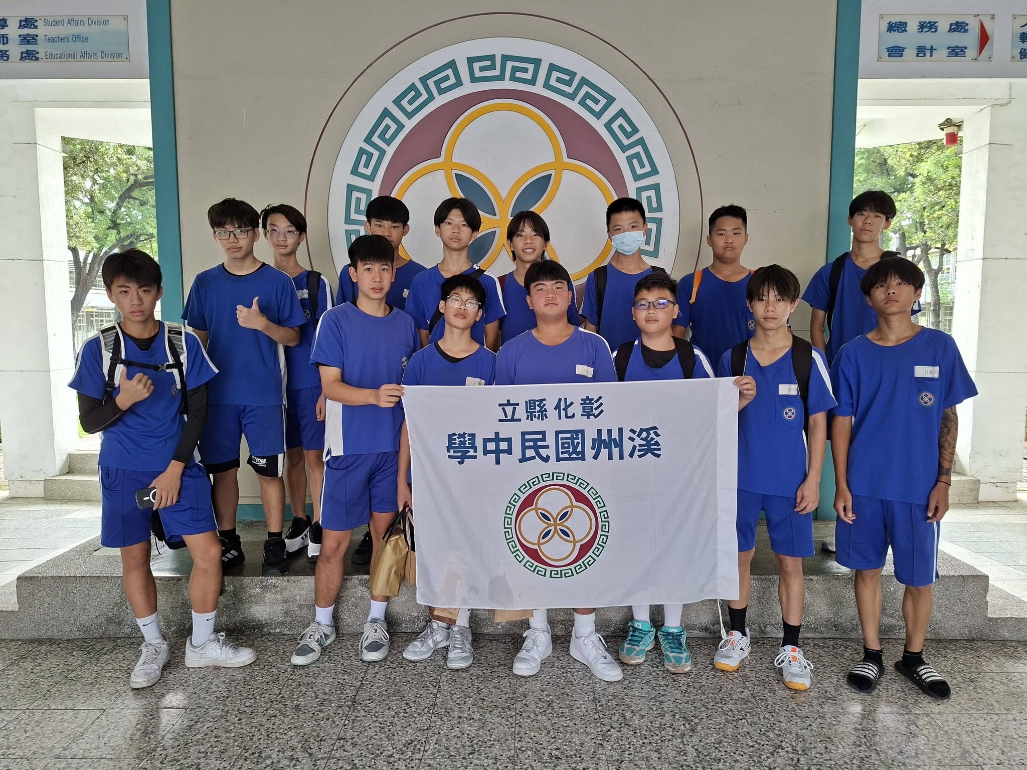 溪州國中學生手持校旗與三校籃球交流賽師生合影