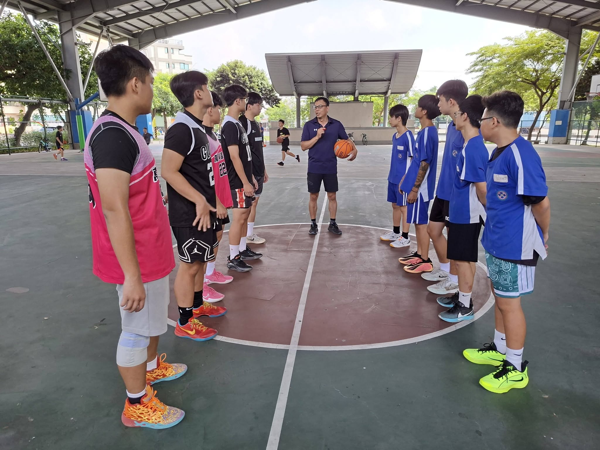 教練在球場上向三校學生講解籃球交流賽規則