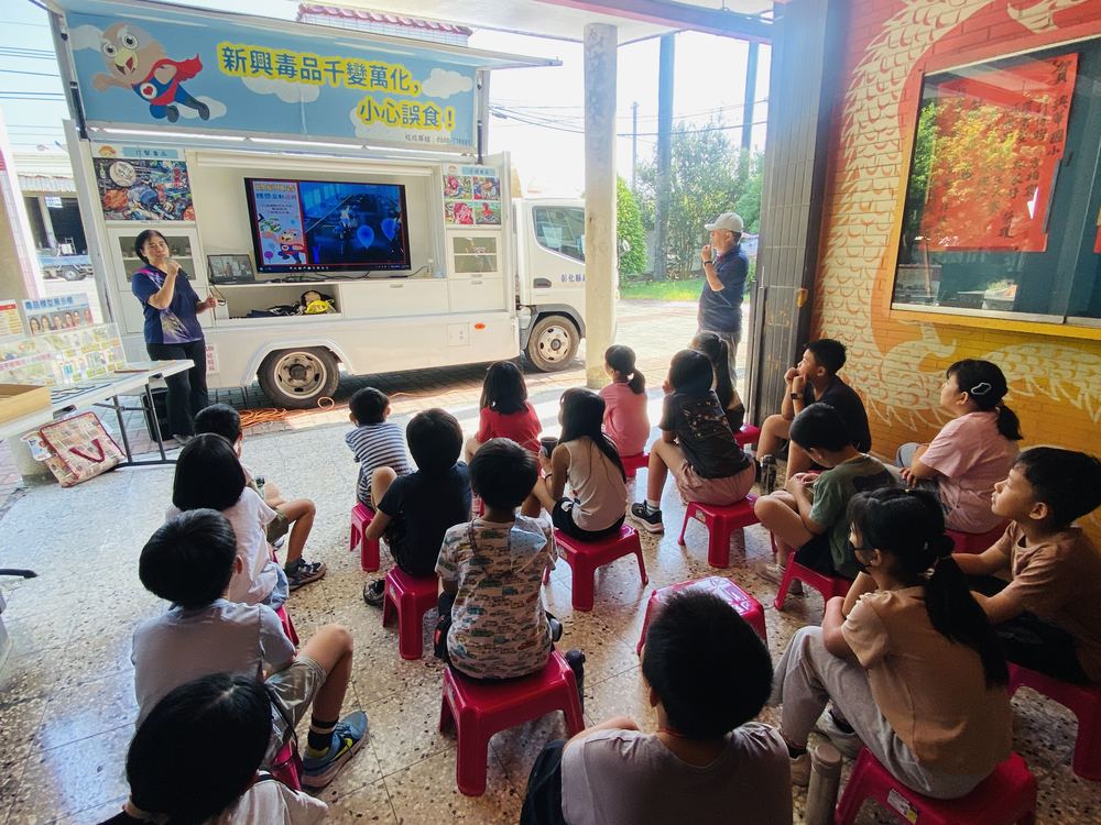 學生坐在行動車前觀看影片 Students sitting in front of the van watching a video on its screen