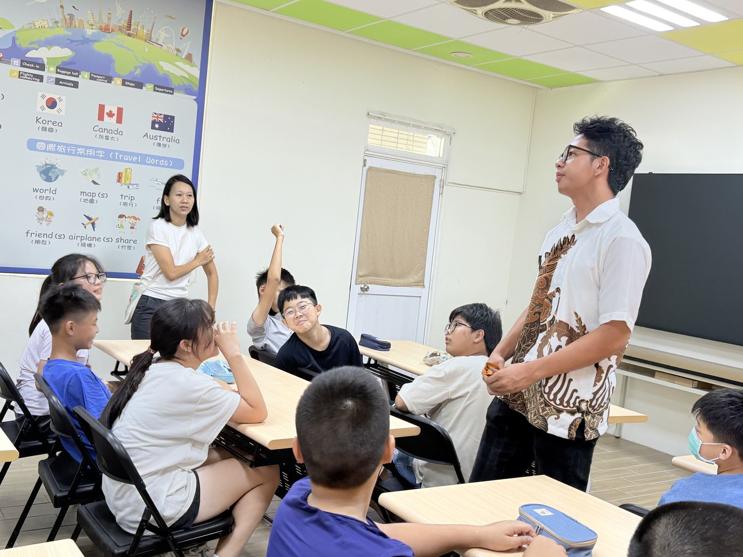 印尼交換學生在教室裡和興華國小學生互動，學生舉手發言 An Indonesian exchange student talking with SingHua students, who raise their hands to answer