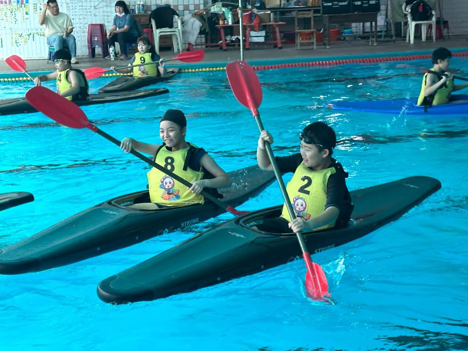 兩位興華國小學生在泳池裡划輕艇 Two SingHua students paddling kayaks in a pool