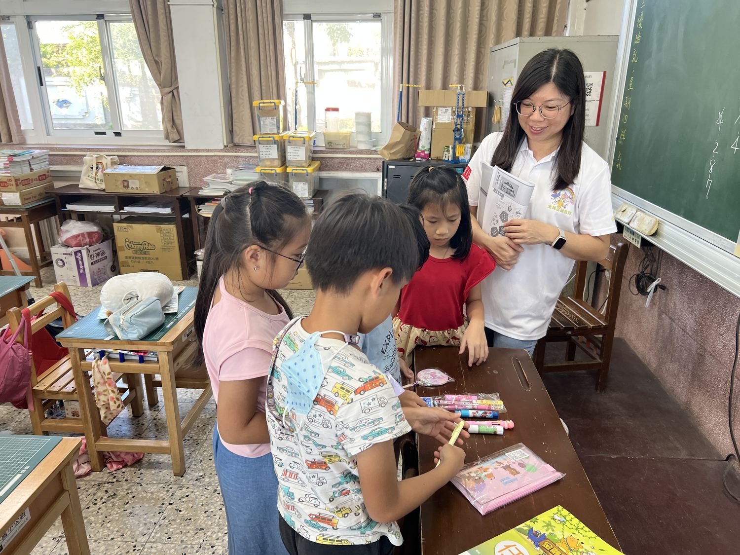 老師在教室裡指導學生使用任務本 A teacher helping students with their task books in class