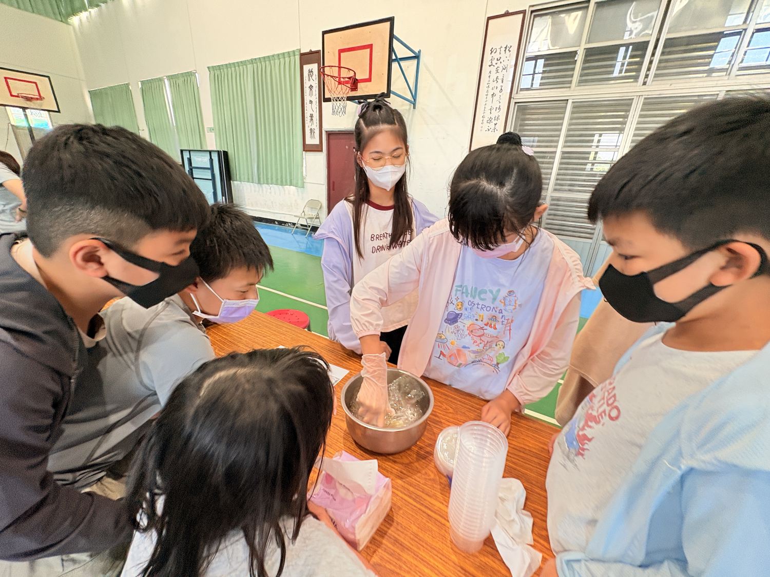 學生圍著鋼盆一起攪拌奶酪材料 Students gathered around a steel bowl, stirring the panna cotta mixture together