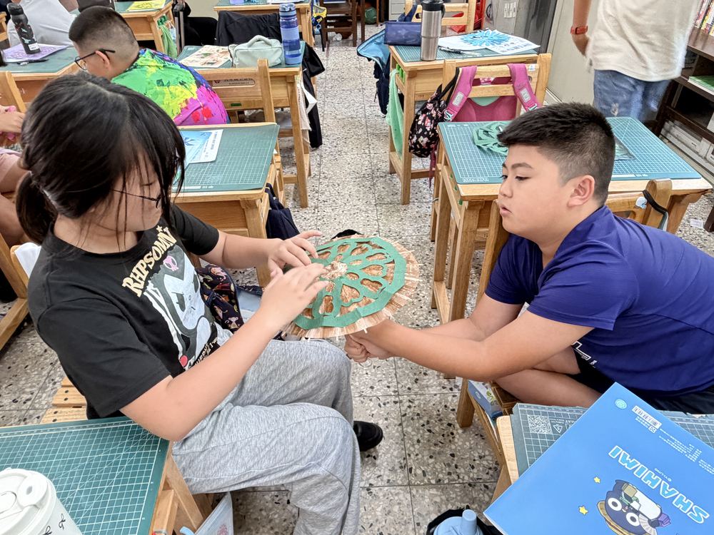兩位學生展示鏤空的剪紙傘面 Two students showing an umbrella with cut-out paper patterns