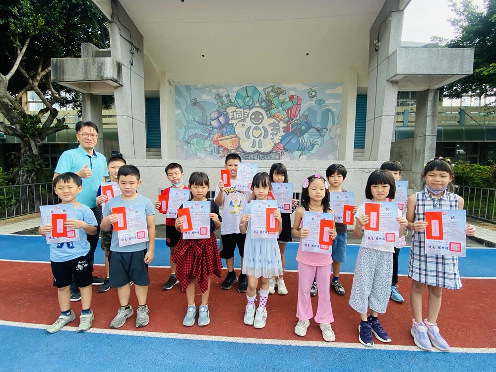獲得表揚的學生在司令台前拿著獎狀 Honored students holding their certificates in front of the stage