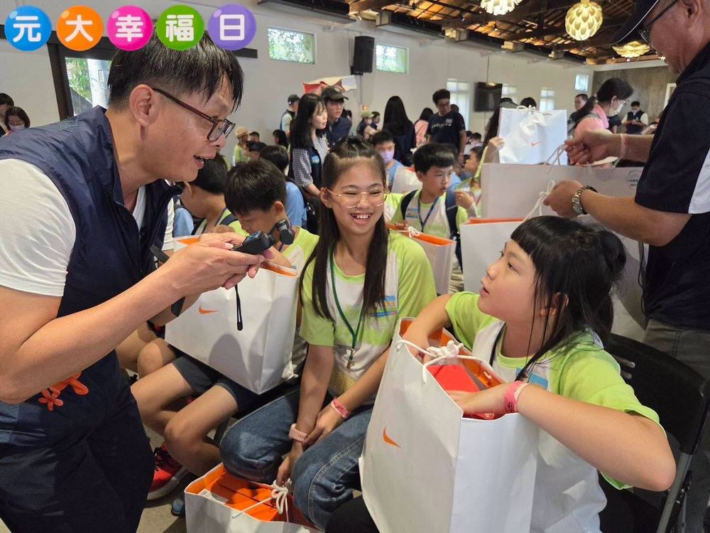 元大志工和孩子們開心聊天，孩子們拿著禮物袋 A Yuanta volunteer chatting happily with children holding their gift bags