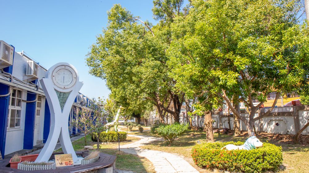 興華國小綠樹成蔭的校園步道，旁邊立著時鐘雕塑