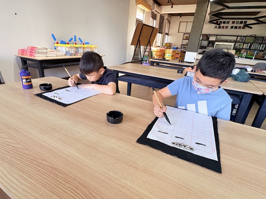 興華國小書法社學生拿毛筆專心練字 SingHua Calligraphy Club students practicing characters with ink brushes