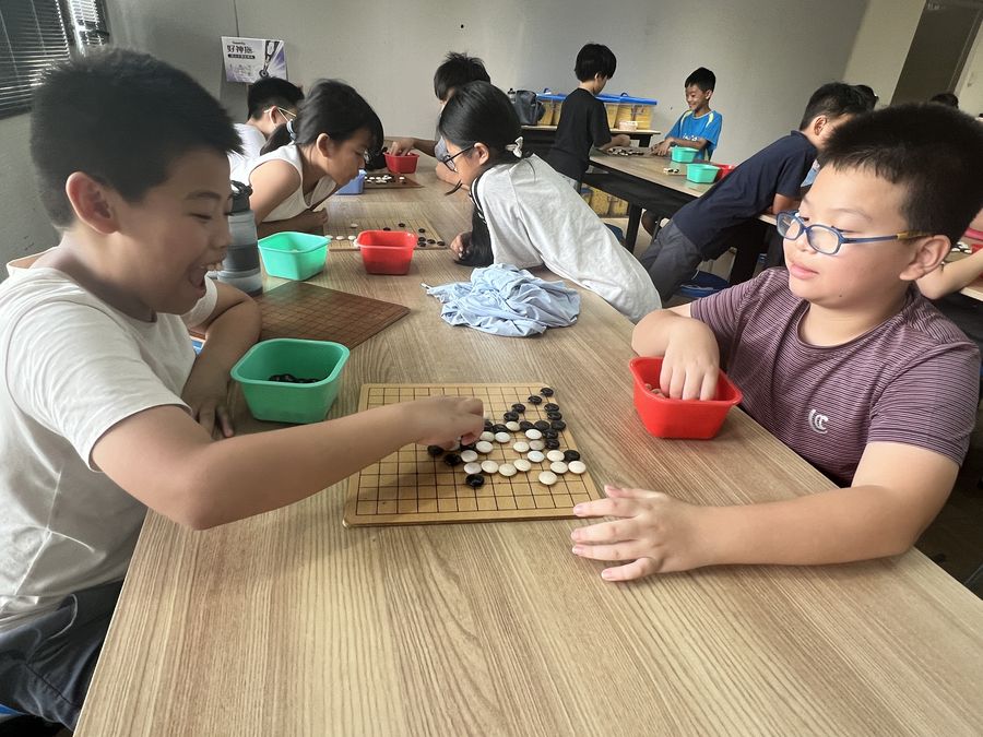 興華國小圍棋社兩位學生對弈，桌上有棋盤與棋子 Two SingHua Go Club members playing a game of Go