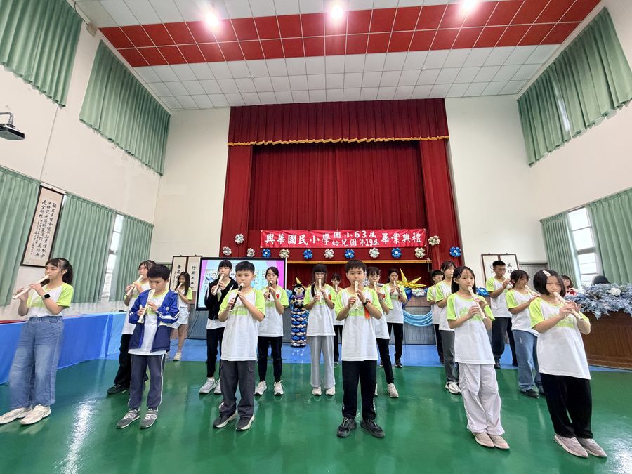 興華國小直笛社學生在禮堂舞台前演奏直笛 SingHua Recorder Club students performing in the school hall
