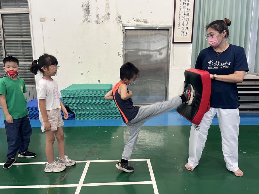 興華國小跆拳道社學生踢向教練手上的護靶 A SingHua Taekwondo Club member kicking a target pad held by the coach