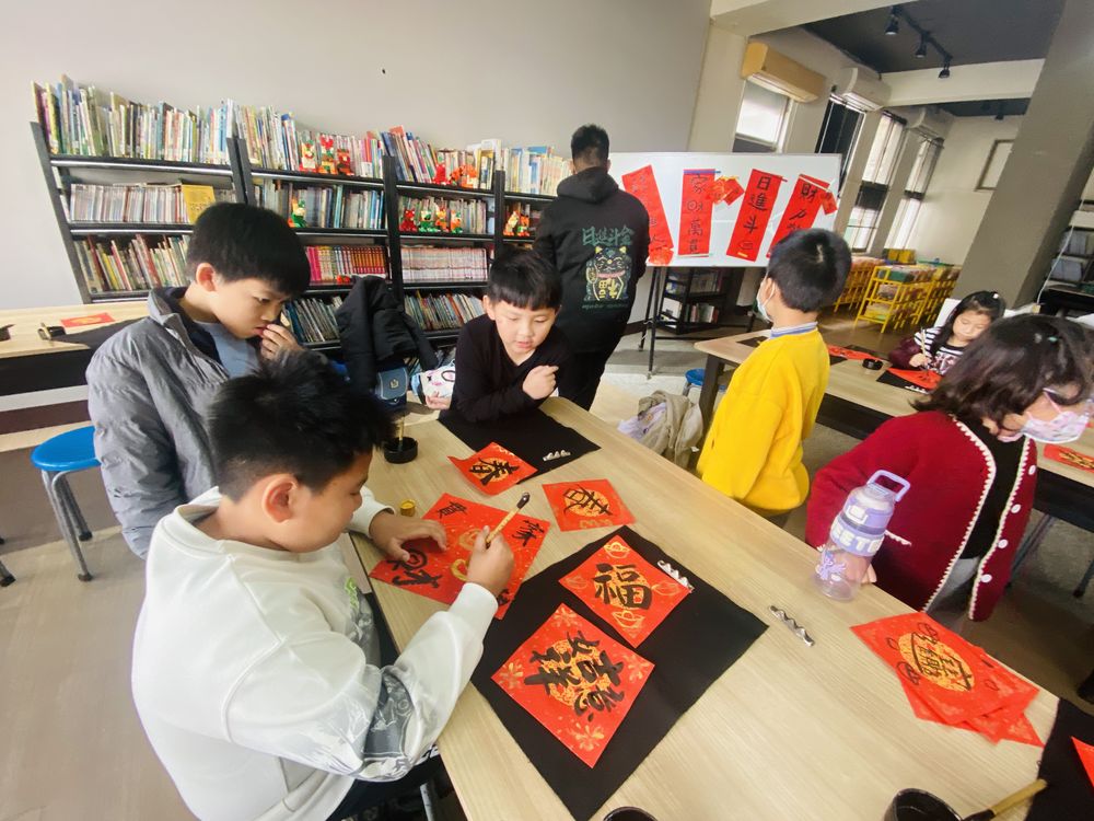 學生在紅色春聯紙上揮毫寫字 Students writing characters on red Spring Festival paper