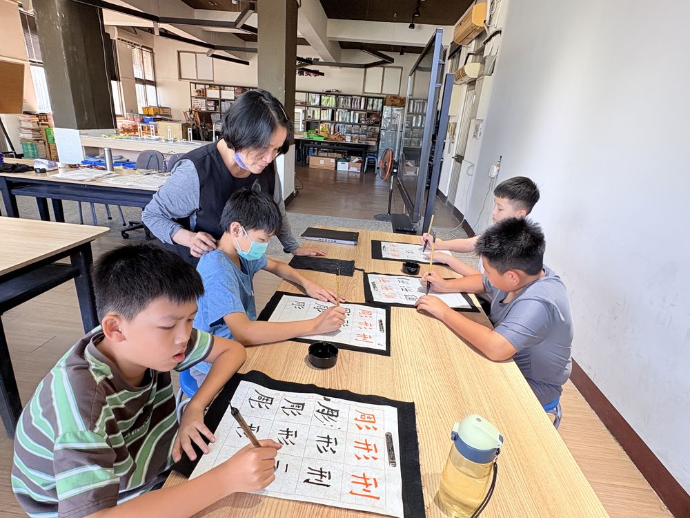 書法社學生在桌前用毛筆練字 Calligraphy Club students practicing characters with ink brushes at their desks