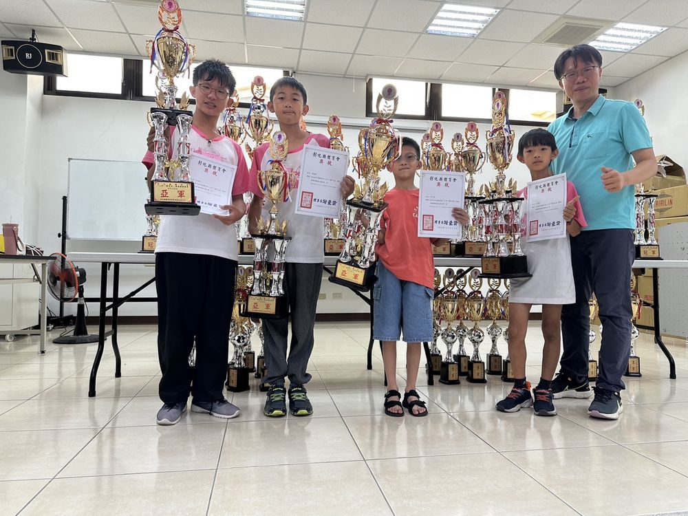 圍棋社學生拿著獎盃與獎狀,和老師一起合照 Go Club members with their trophies and certificates, together with their teachers